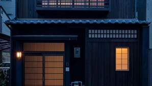 Uma casa japonesa tradicional com fachada de madeira, telhado telhado e porta de madeira deslizante.