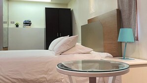 A modern bedroom with a bed, a glass-top table, a nightstand, a lamp, and a wardrobe. - Lowena Cafe and Accommodation (Hobart)