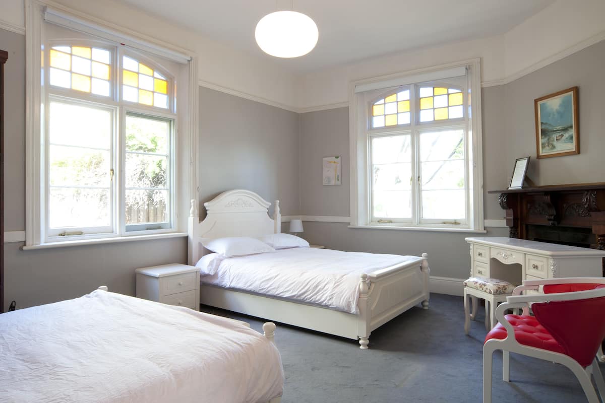 Quarto com duas camas, uma escrivaninha e uma cadeira.