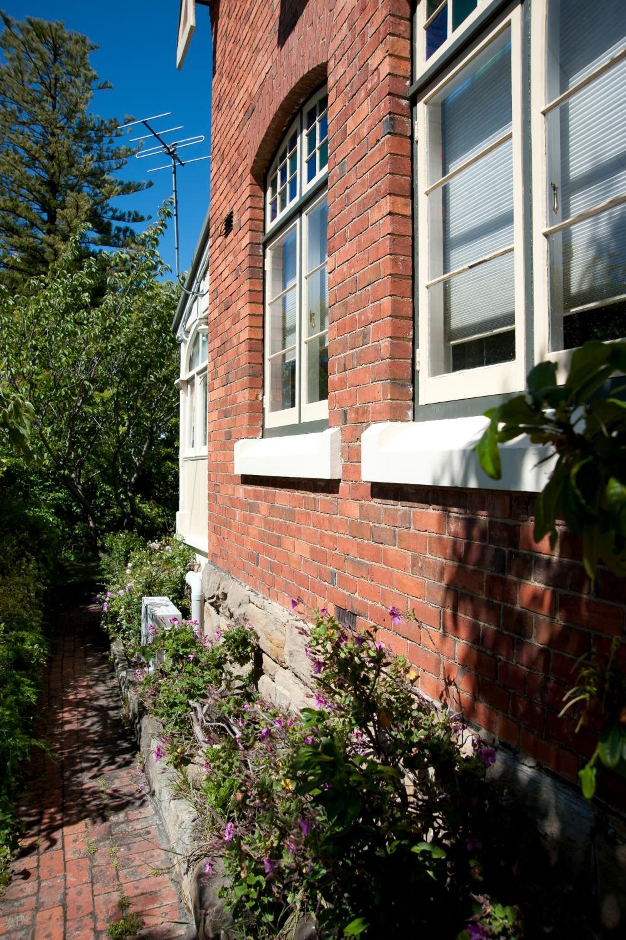 A brick building with white-framed windows and a stone pathway.