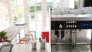 A coffee machine in a bright room with a window, a table, and chairs. - Lowena Cafe and Accommodation (Hobart)