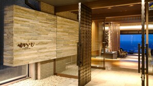 A modern interior with a stone wall, a wooden ceiling, and a seating area with a view. - Atami SEKAIE (Atami)