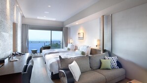 A modern hotel room with a large bed, a sofa, a desk, and a view of the sea. - Atami SEKAIE (Atami)