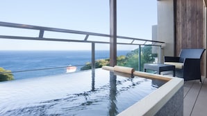 An infinity pool with a view of the ocean, a wooden deck, and a wicker chair. - Atami SEKAIE (Atami)