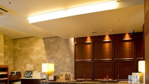 A hotel reception area with a marble counter, wooden paneling, and a tiled floor. - Shizutetsu Hotel Prezio Shizuoka Station Kita (Shizuoka)