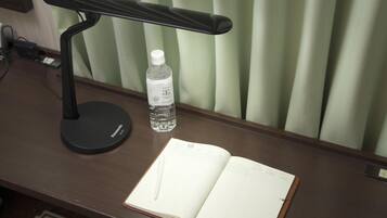 A desk with a black desk lamp, a water bottle, and an open notebook with a pen.