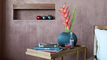 A wooden shelf with books, a vase with a plant, and decorative objects against a textured wall.