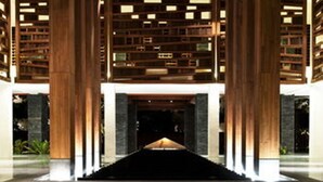 A modern building with a central open space, flanked by tall wooden columns and a series of bookshelves on either side. - Hansar Samui Resort & Spa (Koh Samui)