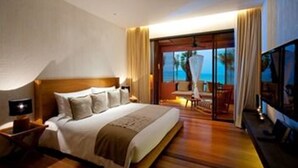 A hotel room with a large bed, a TV, and a balcony with a view of the ocean. - Hansar Samui Resort & Spa (Koh Samui)