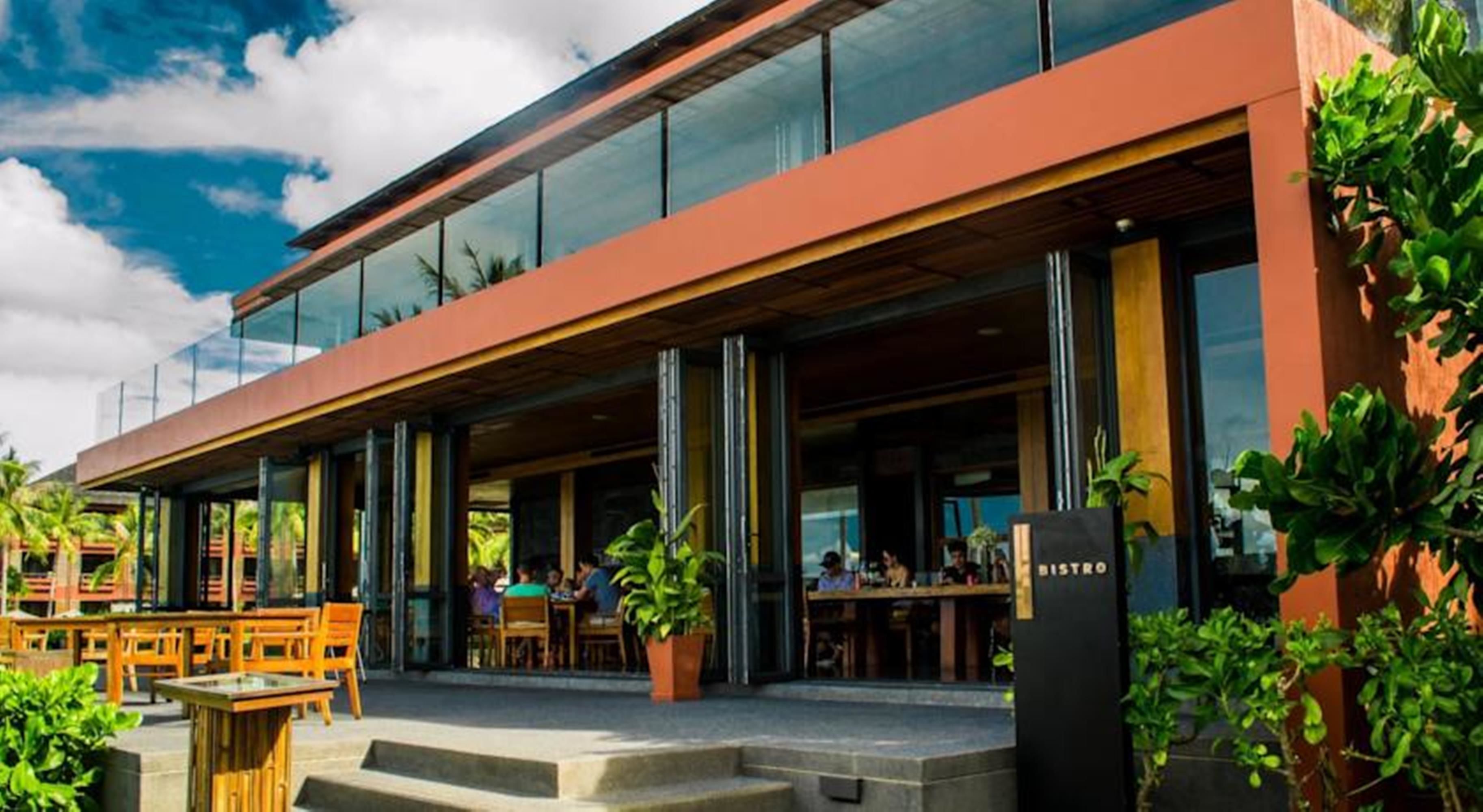 En modern bistro med uteservering, stora fönster och fri utsikt över himlen.