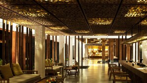 A spacious lobby with a modern design, featuring a central seating area with sofas and tables, a reception desk, and a patterned ceiling. - Hansar Samui Resort & Spa (Koh Samui)