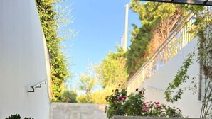 A sunlit patio with a table, a chair, a black mug, and a staircase leading to a garden.