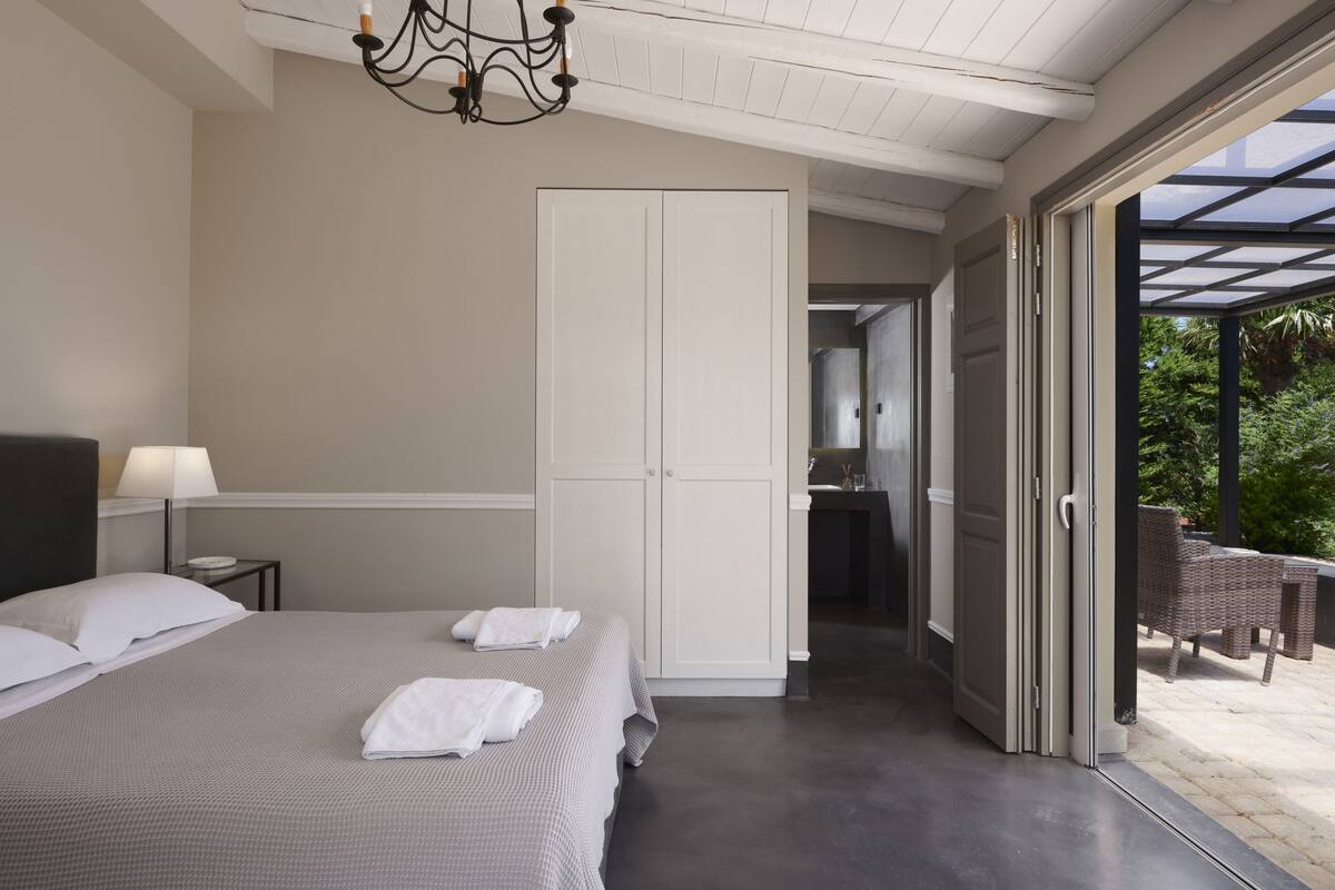 A bedroom with a large bed, a wardrobe, and a bathroom visible through an open door.