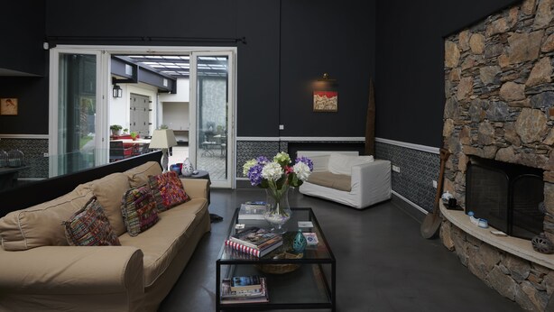 A modern living room with a stone fireplace, a sofa, and a coffee table with books and a vase of flowers.