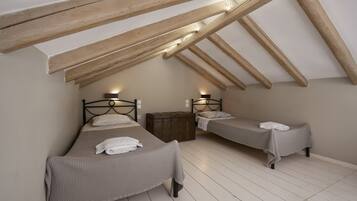 Un dormitorio con dos camas individuales, vigas de madera y un pequeño cofre de madera.