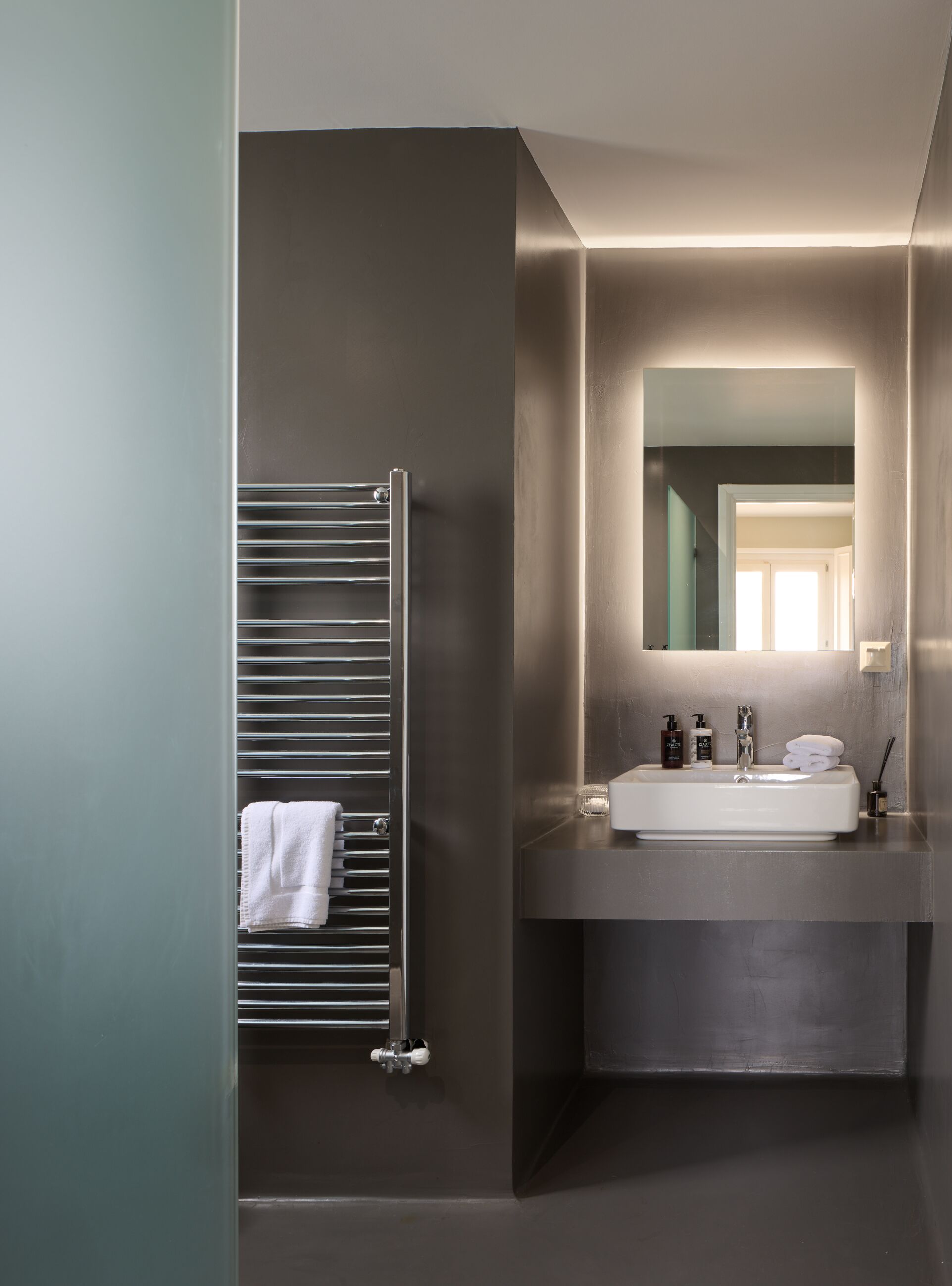 Ein modernes Badezimmer mit integriertem Waschbecken, einem Spiegel und einem Handtuchhalter.