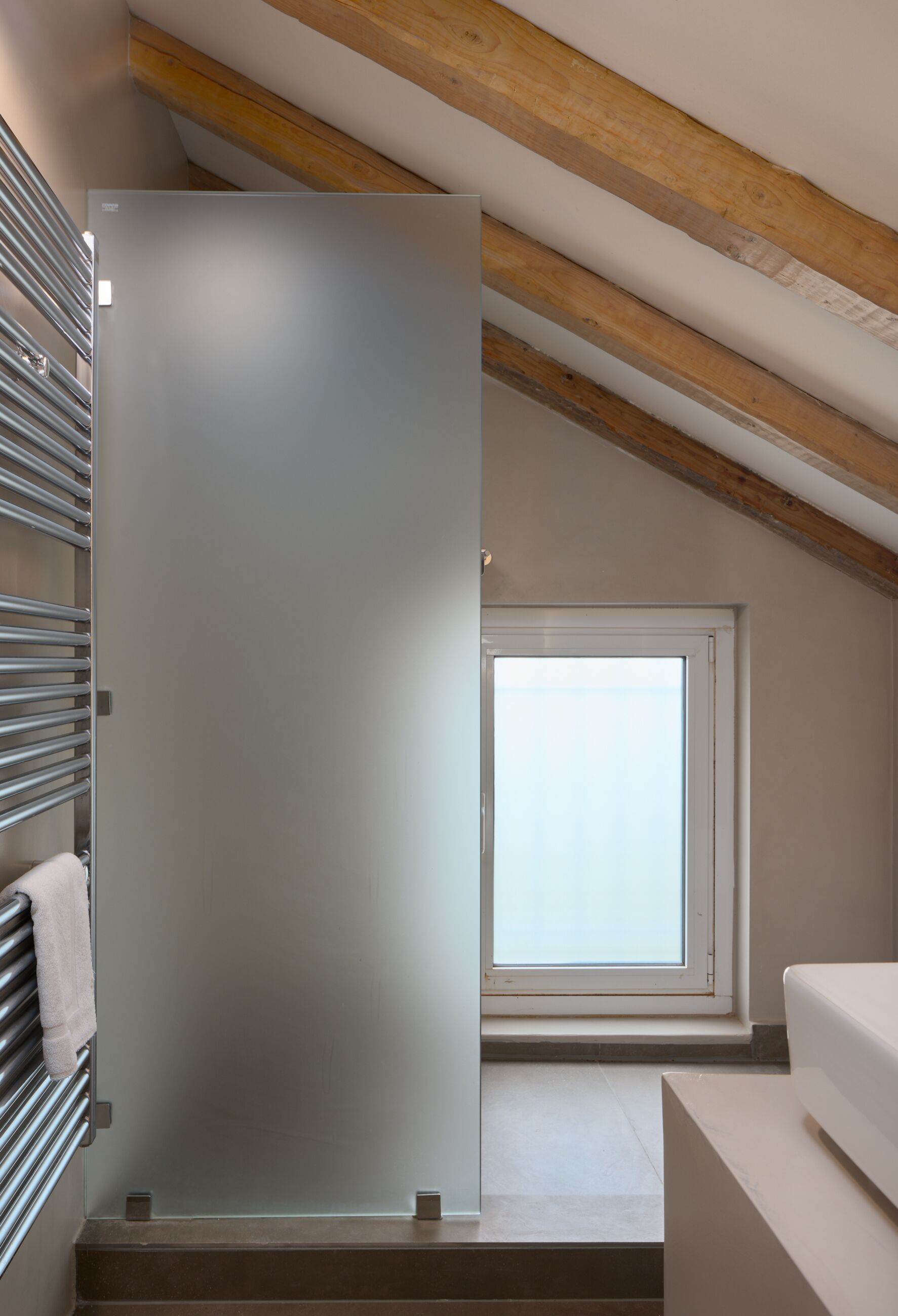 Un baño moderno con cabina de ducha de vidrio, un perchero y una ventana con vistas al exterior.
