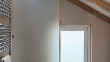 Un baño moderno con cabina de ducha de vidrio, un perchero y una ventana con vistas al exterior.
