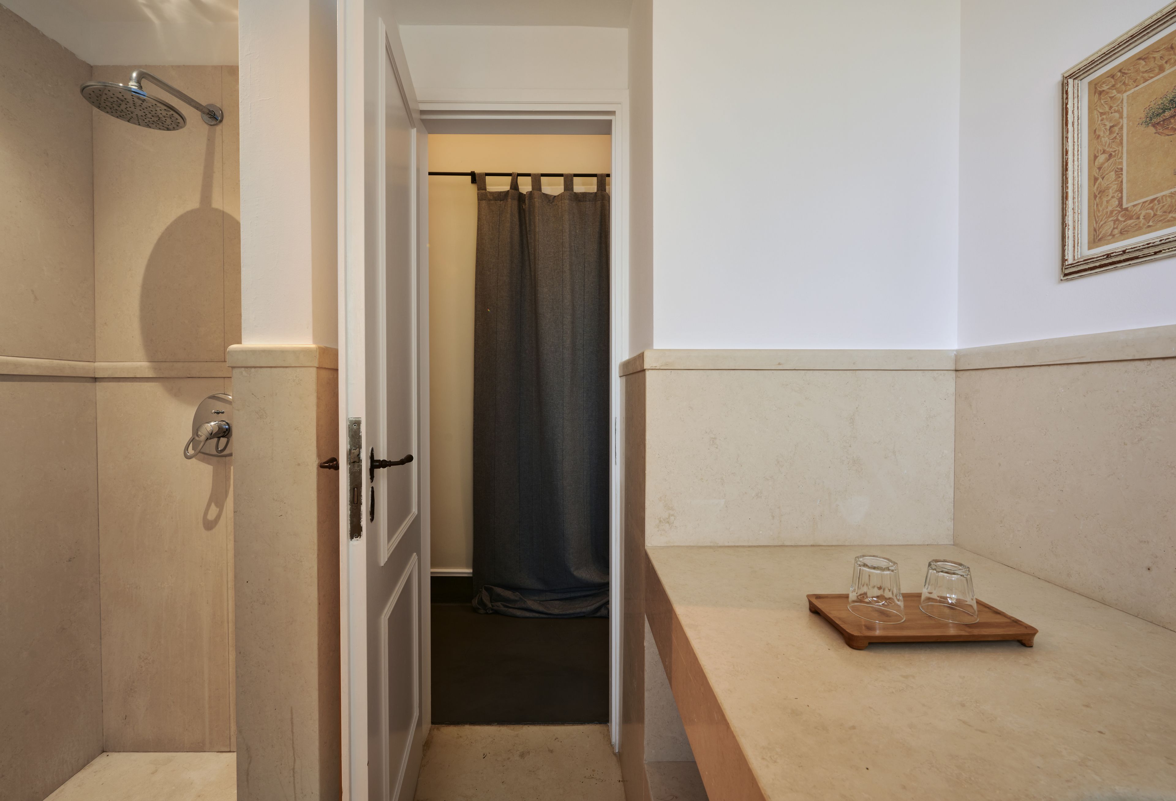 A bathroom with a shower, a towel rack, and a tray with two glasses.