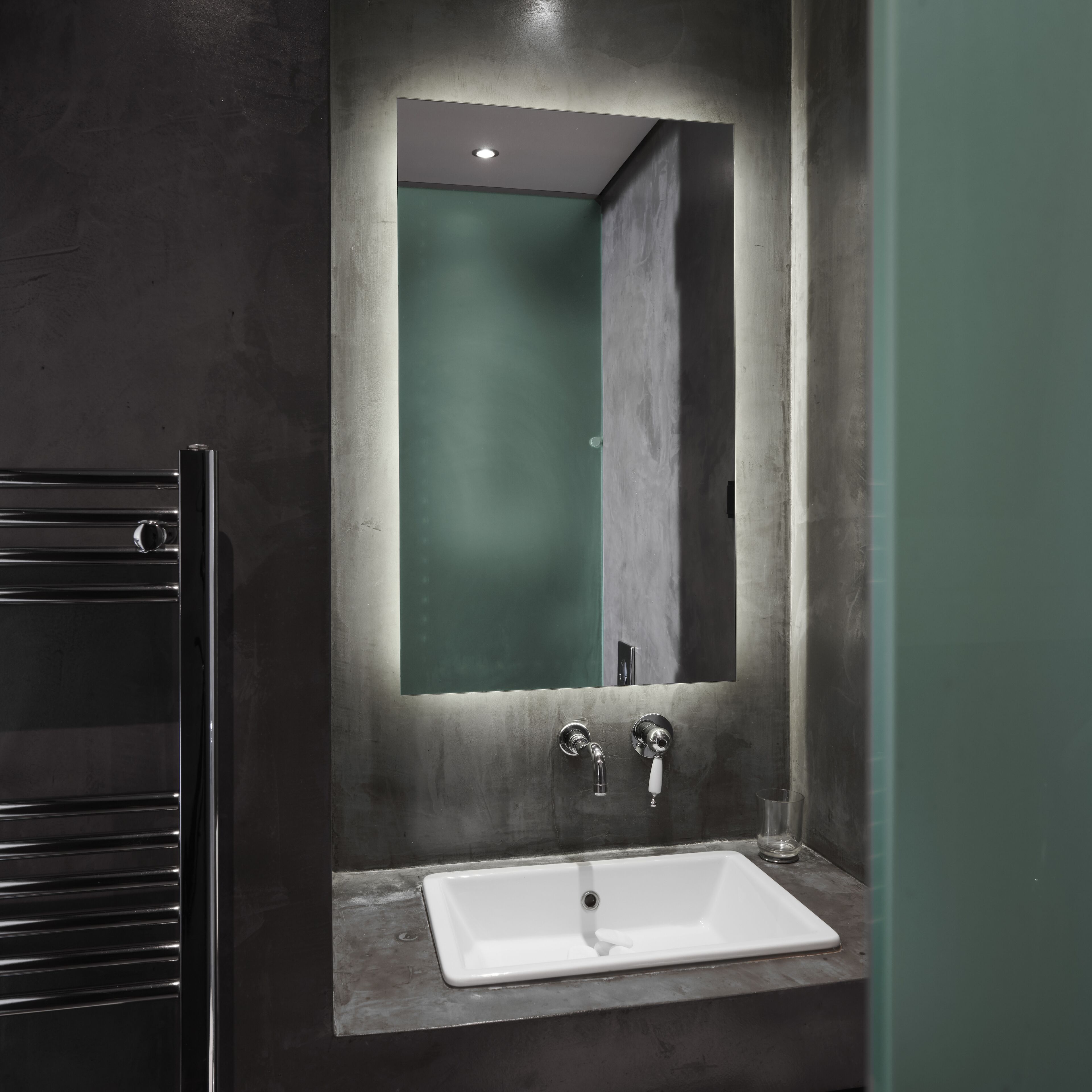 Un baño moderno con un lavamanos rectangular, un espejo y un perchero para toallas.