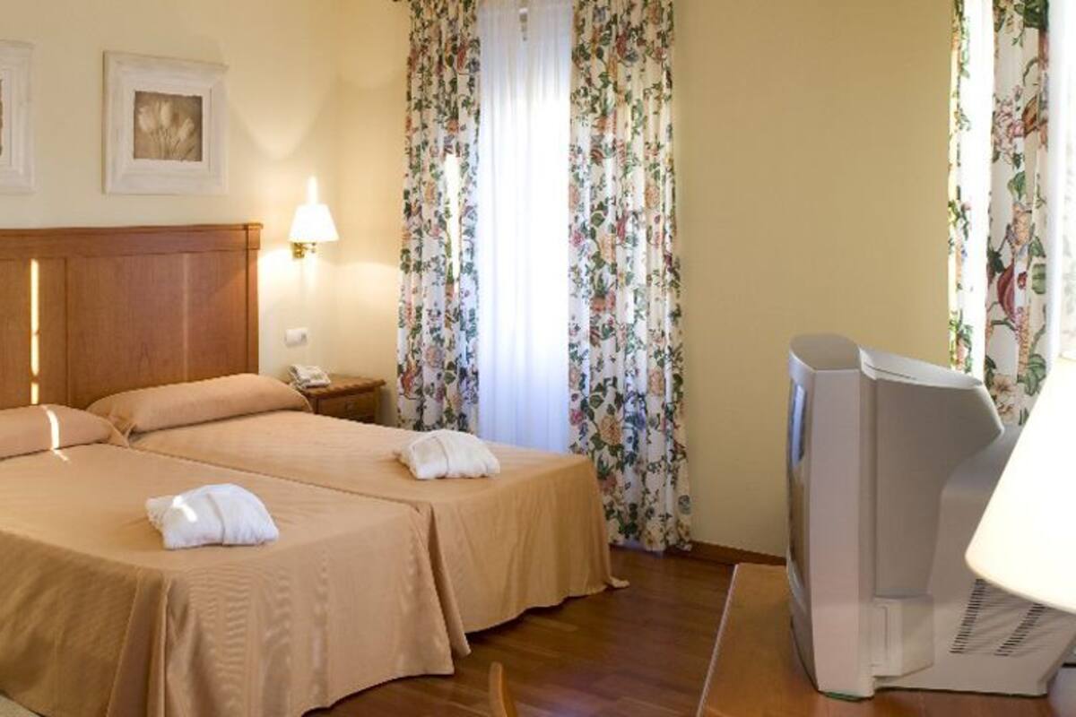 Habitación de hotel con dos camas, televisión, escritorio y silla.