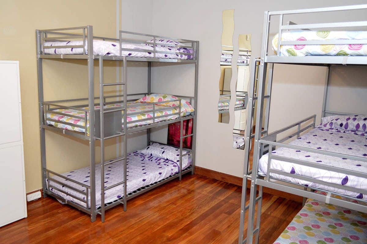 A bunk bed room with a wooden floor, metal railings, and patterned bedding.