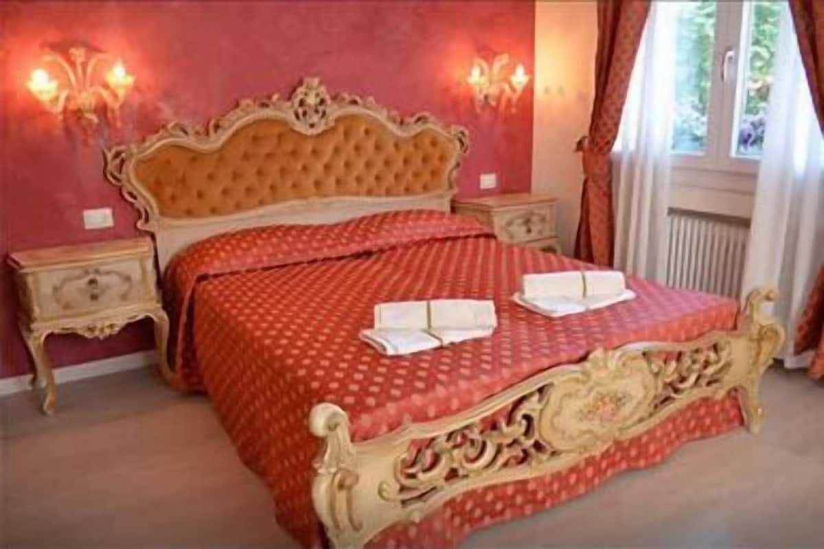 Un dormitorio con una cama grande, dos mesitas de noche y una ventana con cortinas.