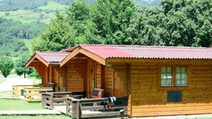 A row of wooden cabins with a red roof, each with a porch and a bench. - Finca El Mazo (Voto)