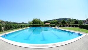 A large, clear swimming pool with a curved edge, surrounded by a well-maintained lawn and hedges. - Finca El Mazo (Voto)