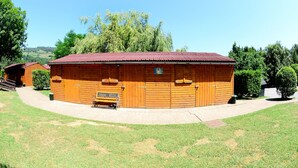 A wooden building with a red roof, a bench, and a paved walkway. - Finca El Mazo (Voto)