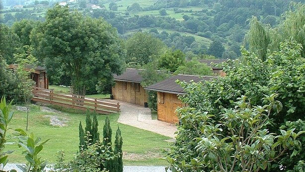 A rural setting with wooden buildings, a wooden bridge, and a grassy area. - Finca El Mazo (Voto)