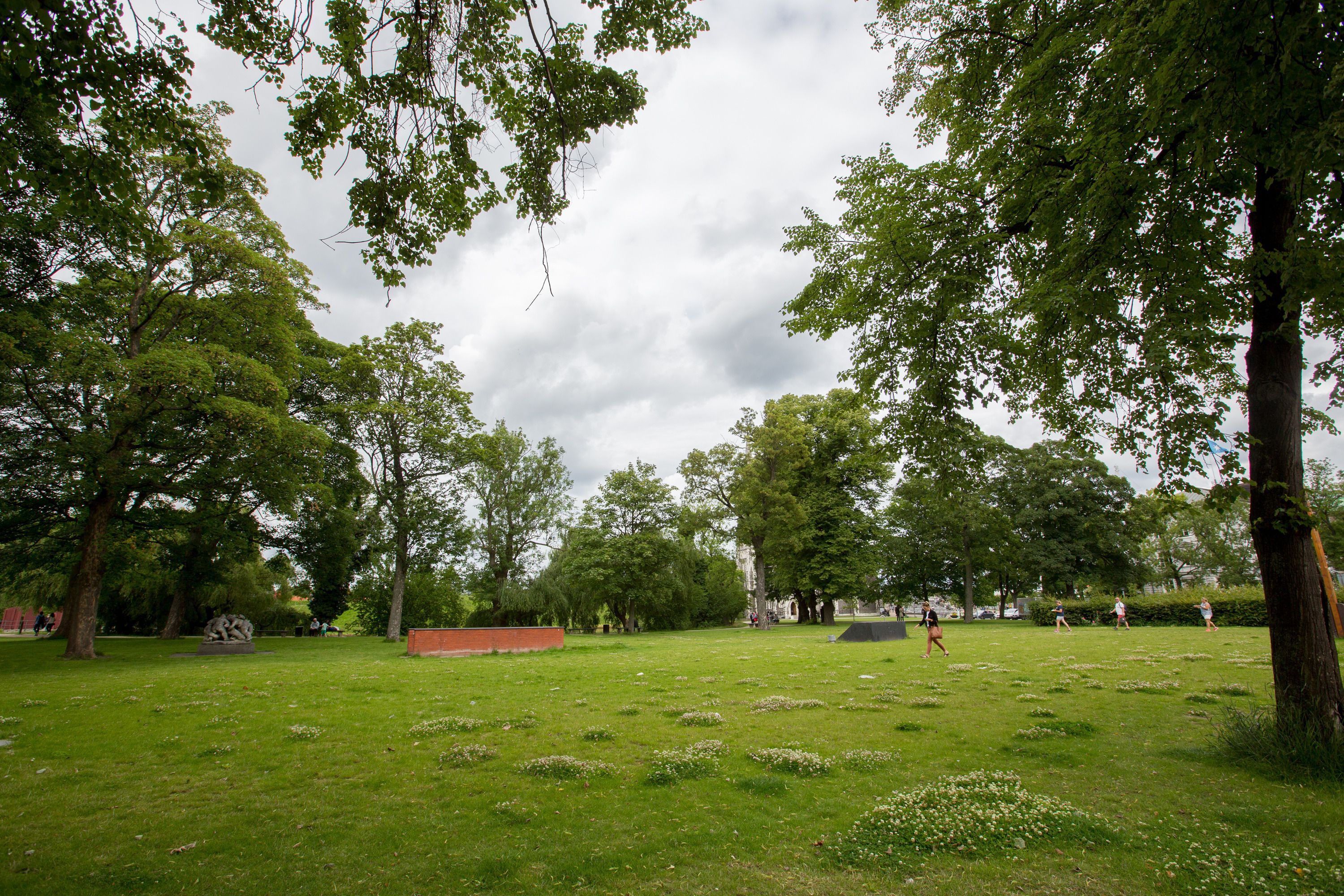 A park with a grassy area, trees, and a sculpture.