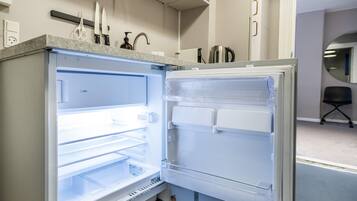 Eine moderne Küche mit einem eingebauten Kühlschrank, einer Kaffeemaschine und einem Wasserkocher auf der Arbeitsfläche.