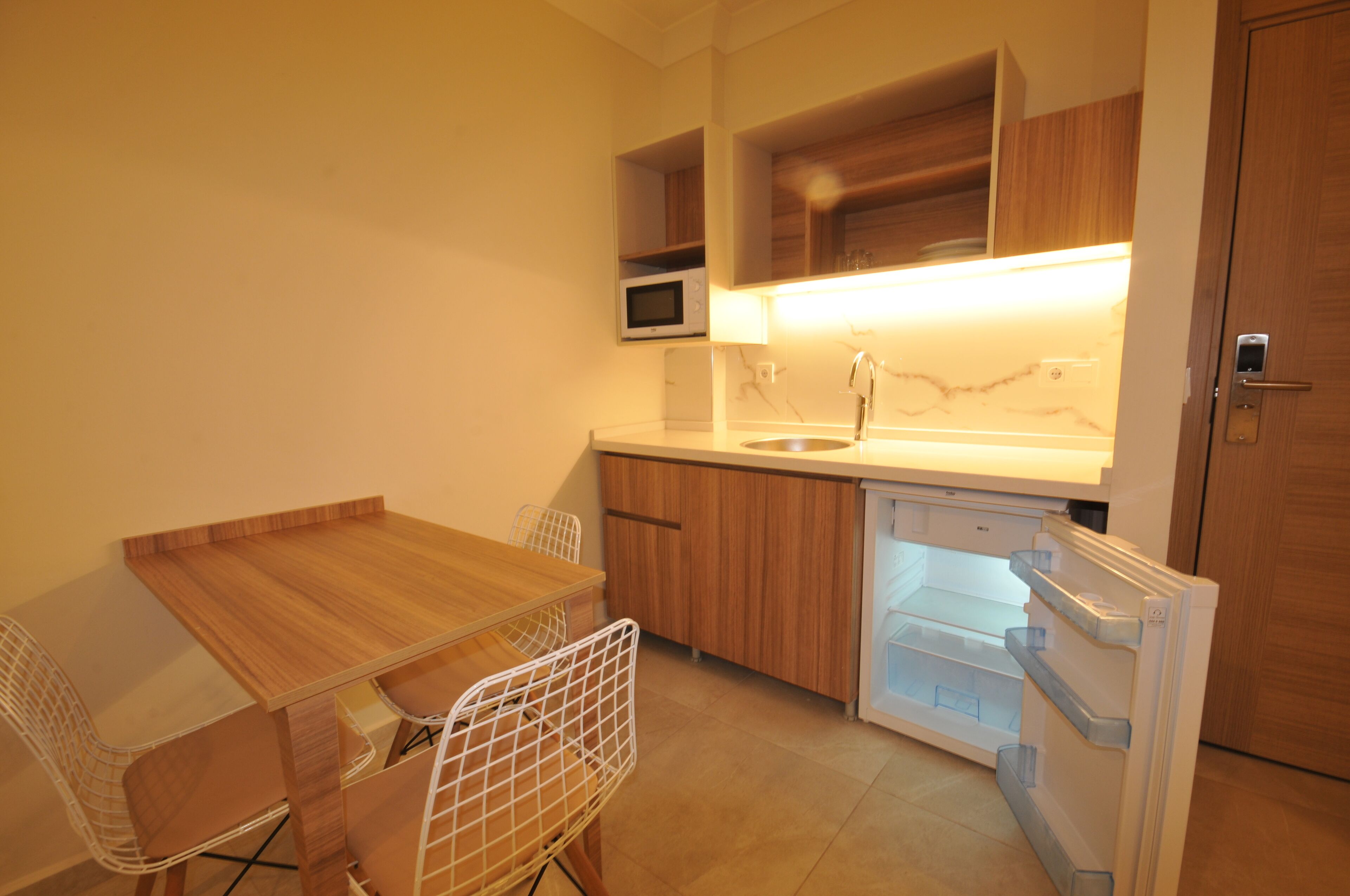 Cocina pequeña con una mesa y sillas de madera, un microondas y un refrigerador.