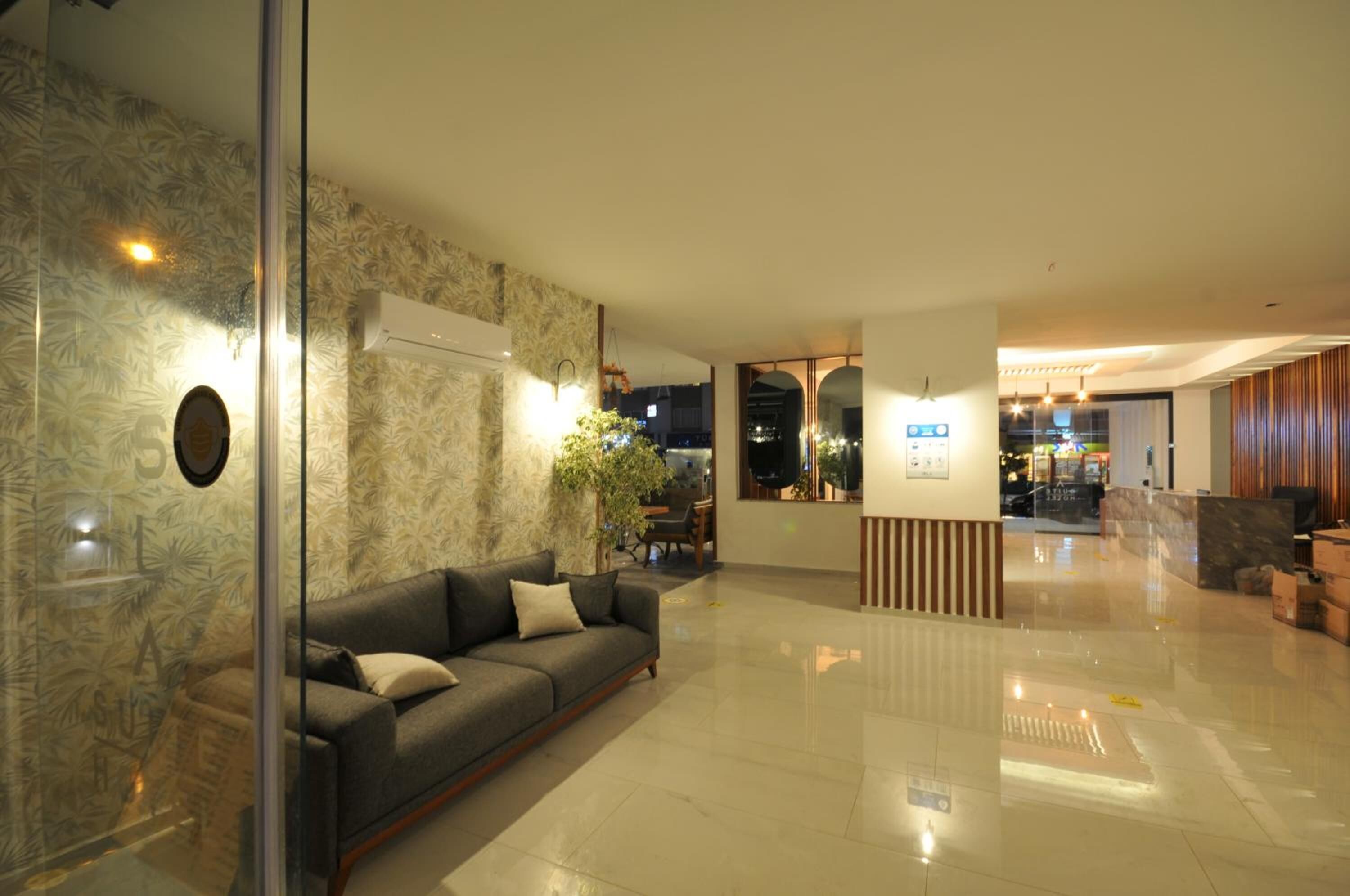 Een moderne lobby met een glazen scheidingswand, een bank, een receptiebalie en een gepolijste vloer.