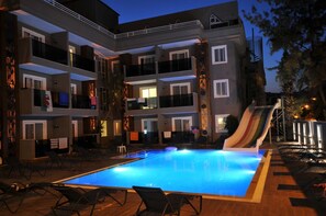 A multi-story hotel with a swimming pool, lounge chairs, and a slide. - Isla Apartments (Marmaris)