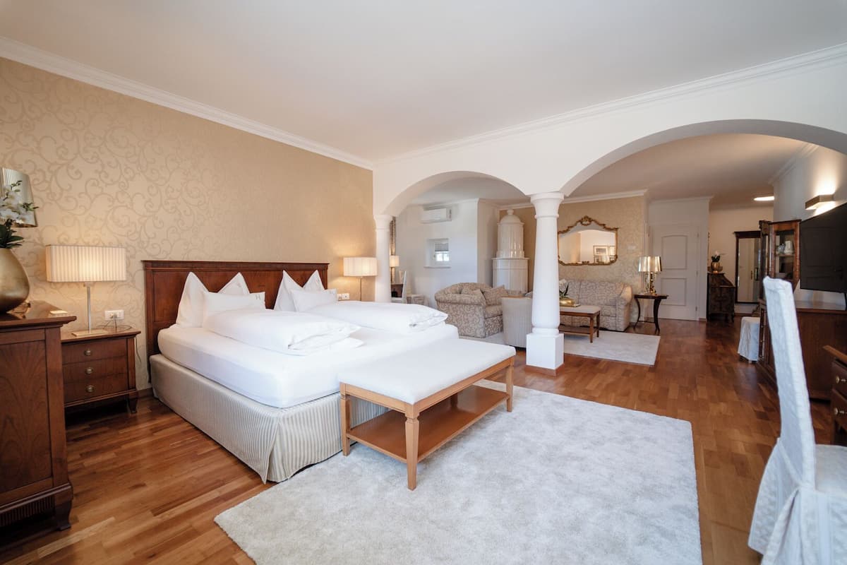 A hotel room with a large bed, a sitting area with a sofa, and a dining table.
