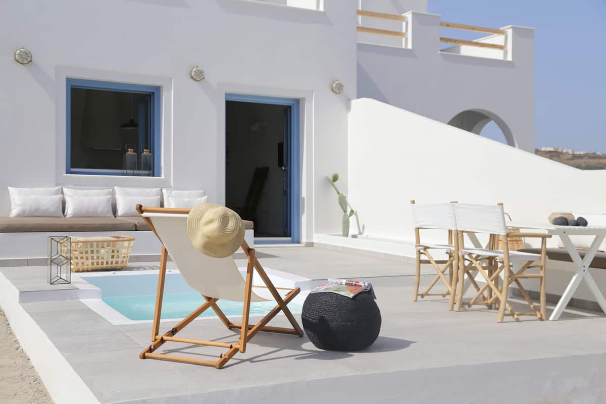 Zona d'estar exterior moderna amb piscina, una cadira relaxant i una taula de menjador.