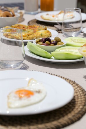 A breakfast setting with plates of food, including eggs, avocado, and olives.