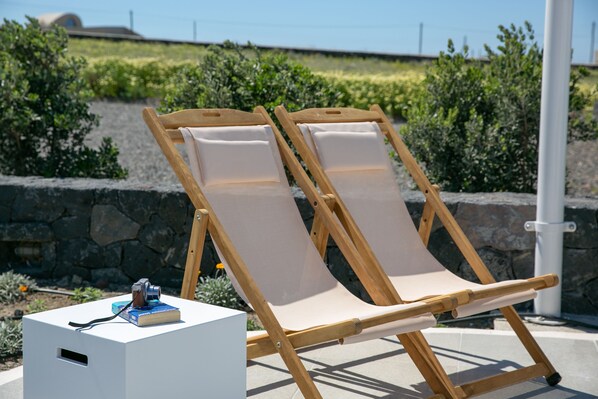 Two wooden lounge chairs with canvas seats and a white box with a camera on top.
