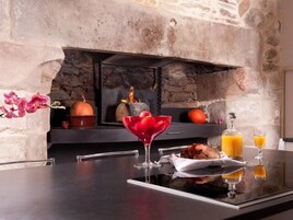 Une cuisine moderne avec une cheminée en pierre, une table en verre et une orchidée décorative.