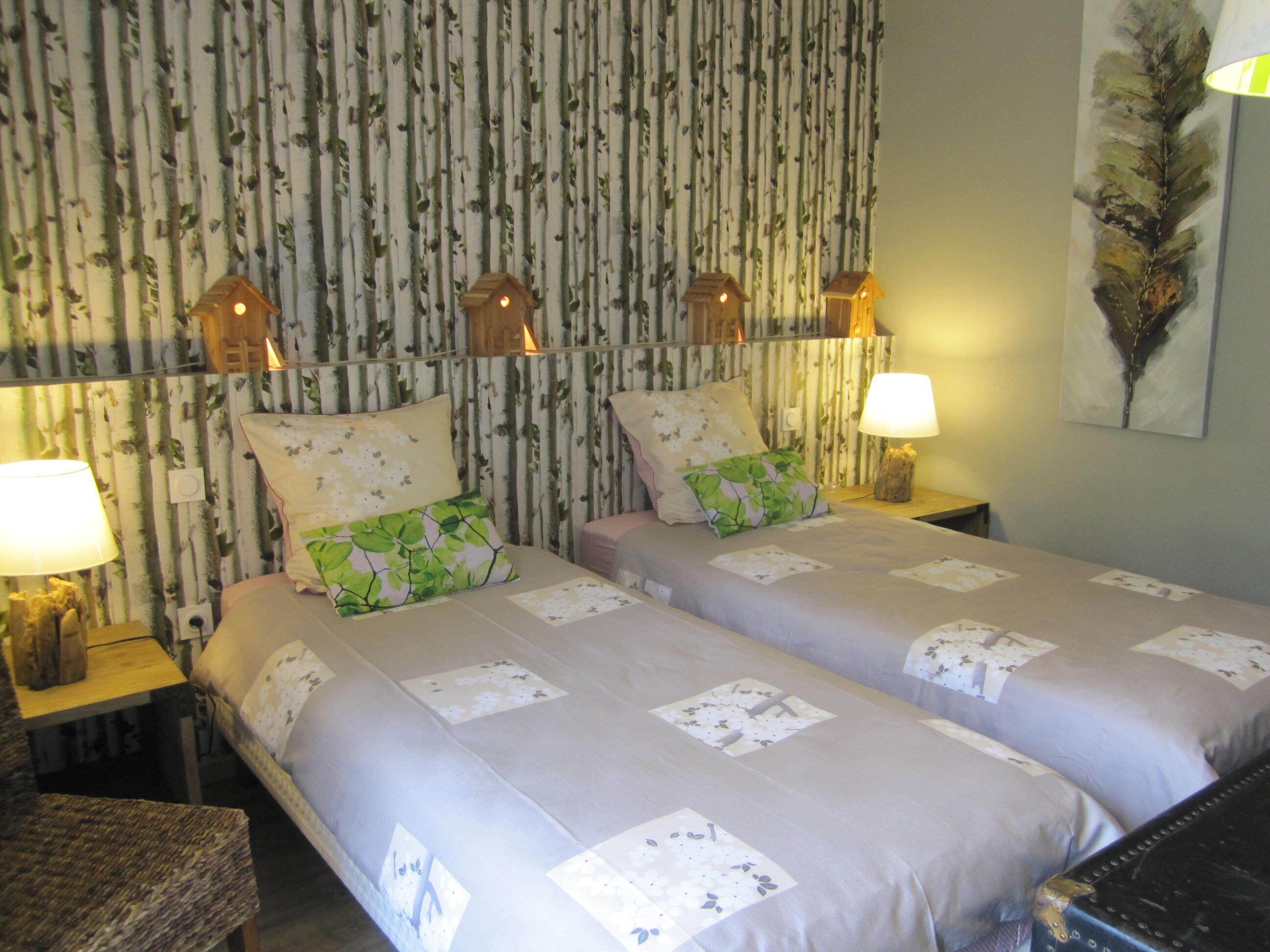 Una cama doble con ropa de cama floral, dos lámparas de noche y una pared con rayas verticales y adornos de casas para pájaros.
