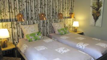 Una cama doble con ropa de cama floral, dos lámparas de noche y una pared con rayas verticales y adornos de casas para pájaros.