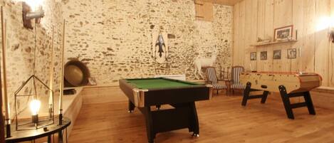 A room with a pool table, two foosball tables, and a billiards table.