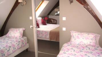 A bedroom with two beds, each with floral bedding, a skylight, and a wooden ceiling beam.