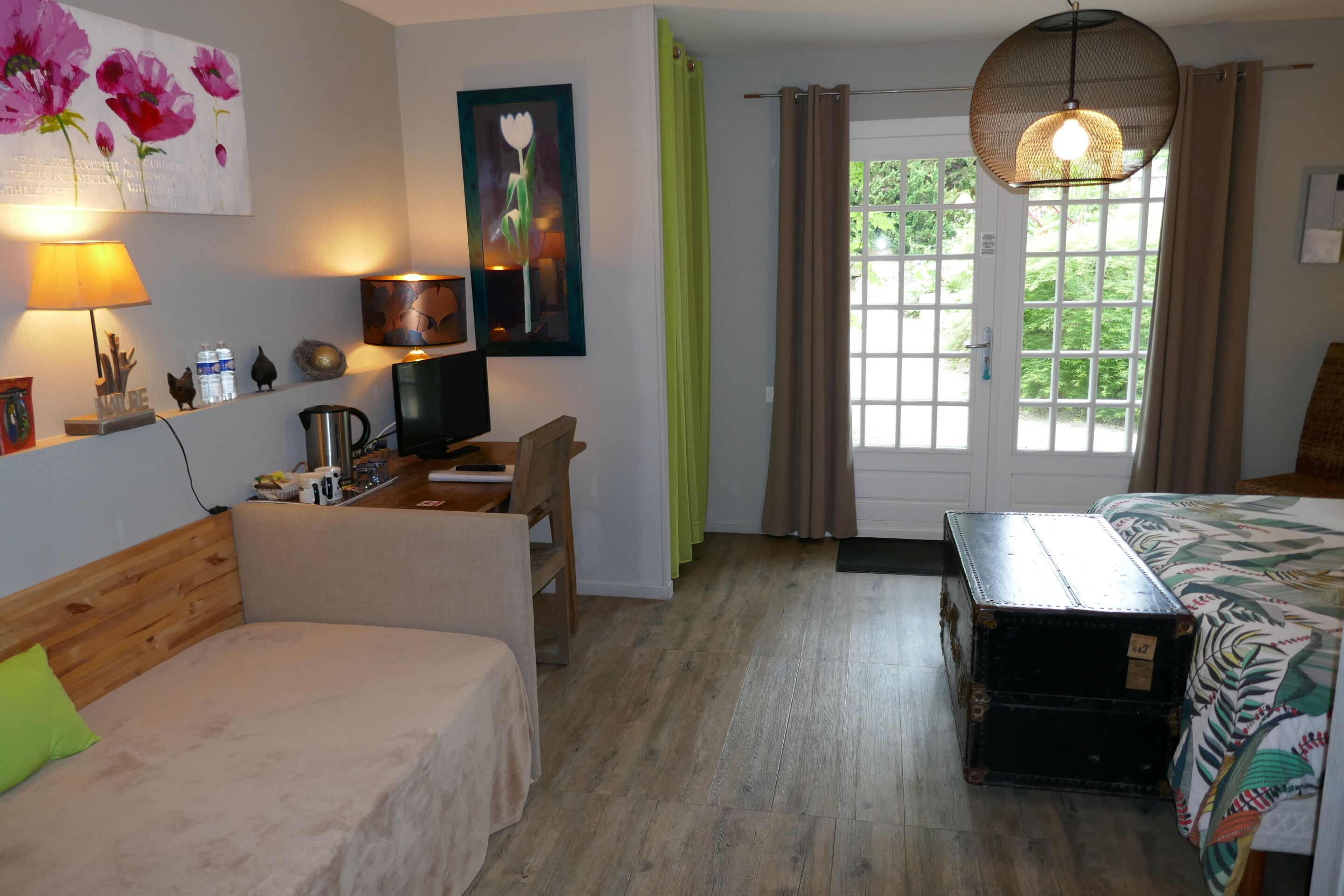 Een gezellige kamer met een bed, een bureau, een stoel, een lamp en een raam met gordijnen.