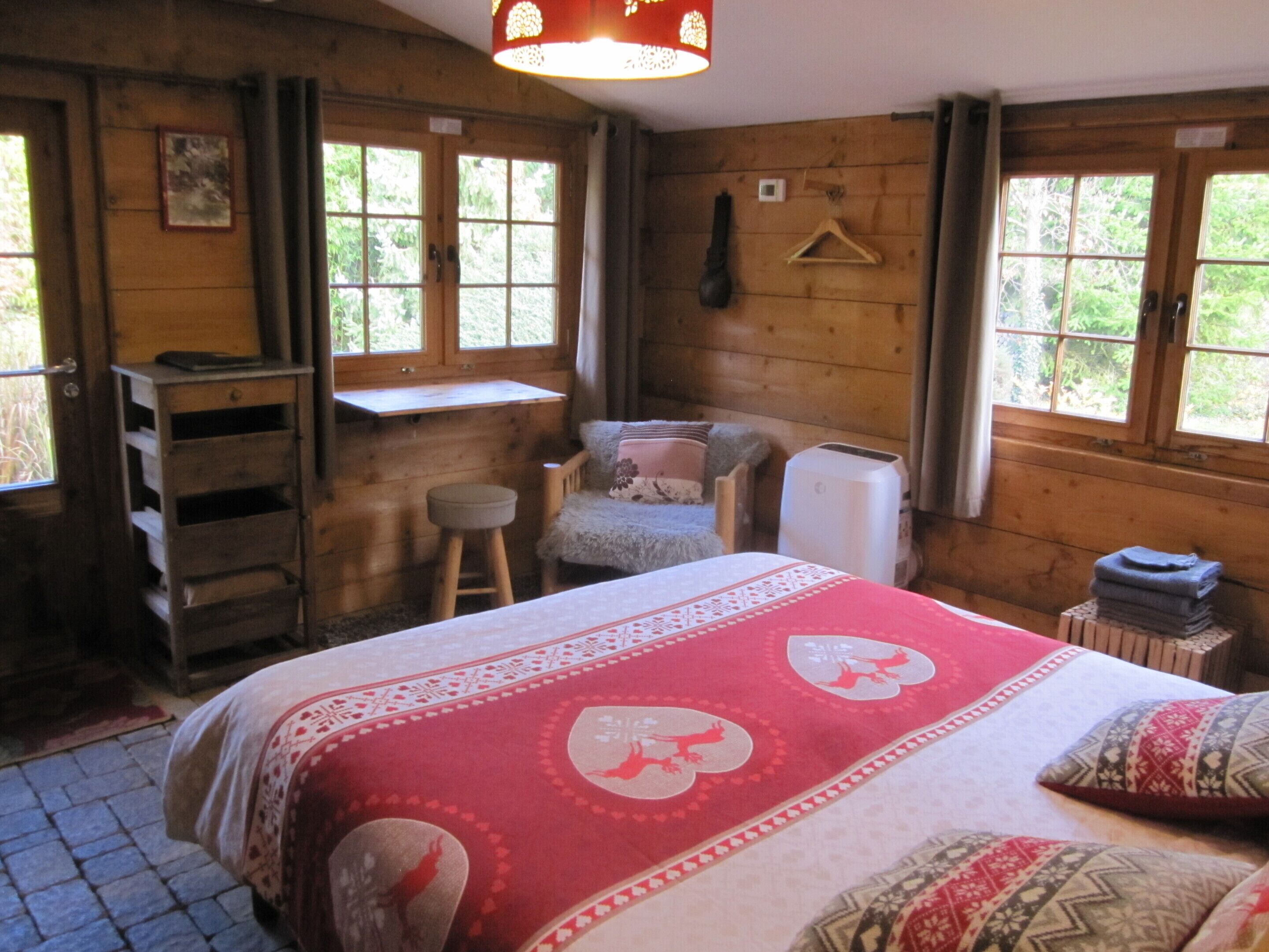 A cozy wooden room with a bed, a desk, and a chair.