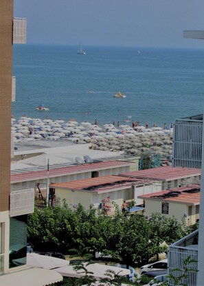 A coastal hotel with multiple balconies overlooking the sea, a beach area with umbrellas, and a clear view of the ocean. - Hotel Villa Fiorita (Cervia)