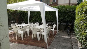 Une tente blanche avec une table et des chaises disposées sur un tapis à motifs.