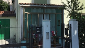 Un bâtiment à deux étages, doté d’une façade verte, d’un toit en tuiles et d’un chiffre « 7 » bien visible sur un pilier blanc.